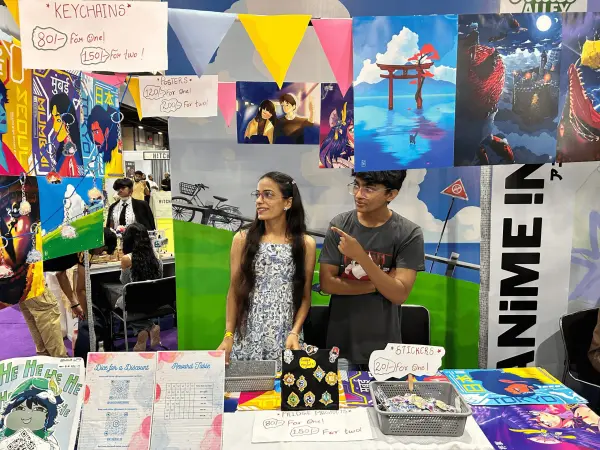 Kumani booth at Artist Alley with posters, keychains, and colourful displays